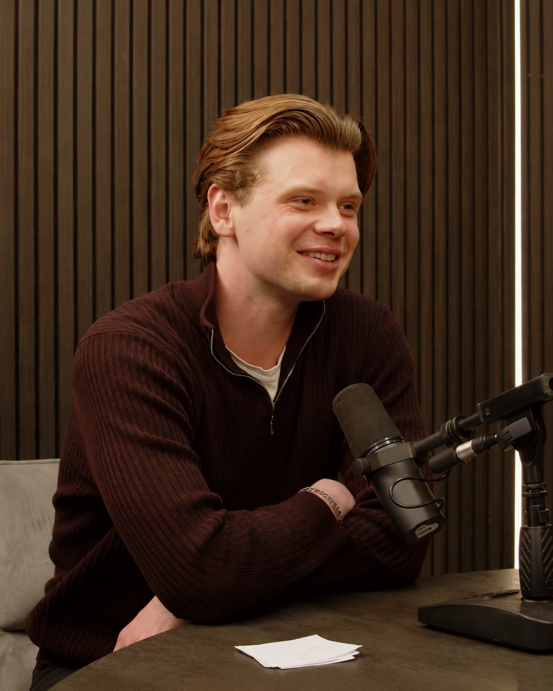 Dylan recording a podcast in a burgundy quarter-zip